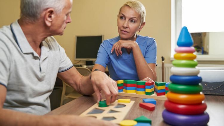 Therapeutin beaobachtet älteren Patienten beim Gedächtnistraining