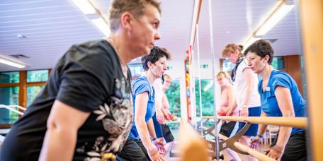 Therapiegruppe Physiotherapie Patientengruppe trainiert in der Physiotherapie vor einem großen Spiegel