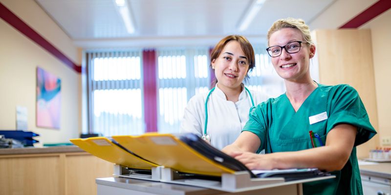 Ärztin und weibliche Pflegekraft besprechen Patientenakten
