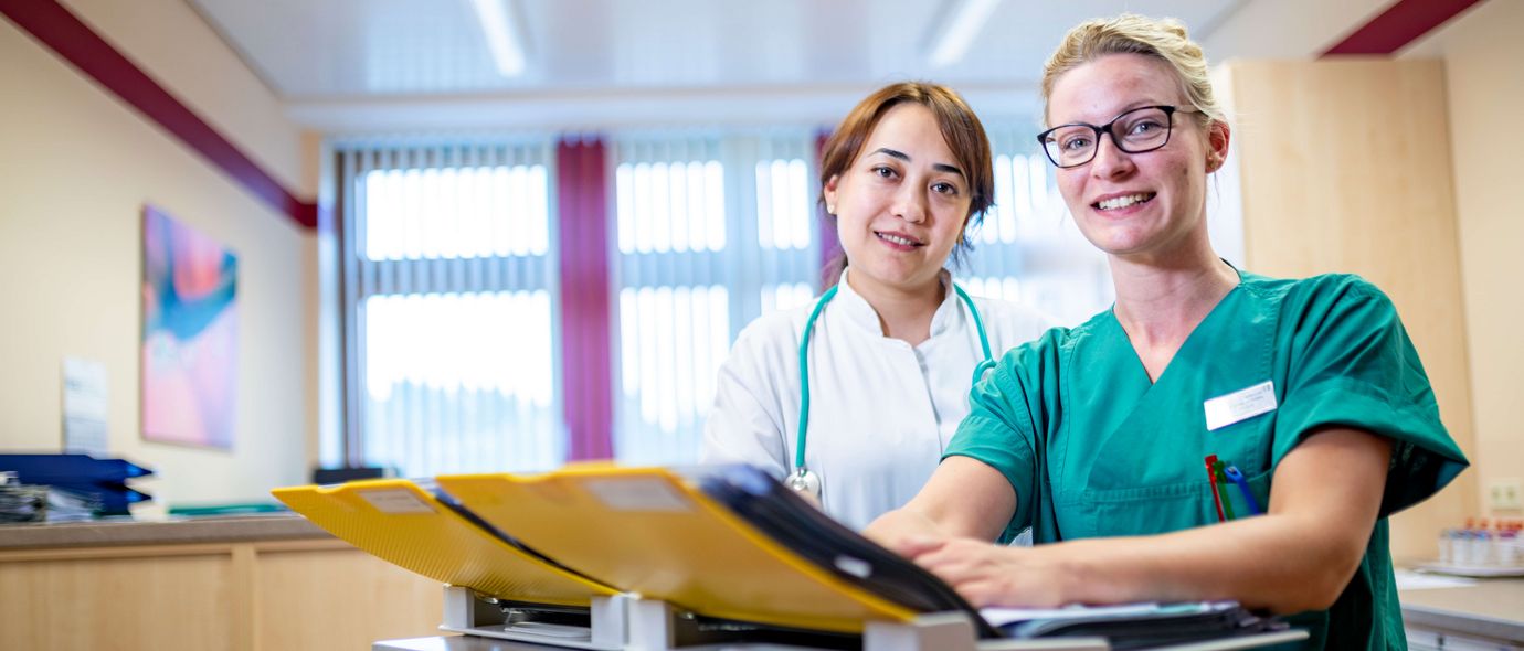 Ärztin und weibliche Pflegekraft besprechen Patientenakten