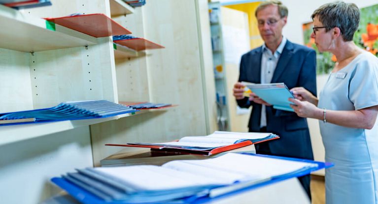 Chefarzt Psychosomatik und Therapeutin besprechen Patientenakten