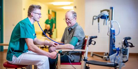 Pflegekraft misst bei einem älteren Patienten den Blutdruck