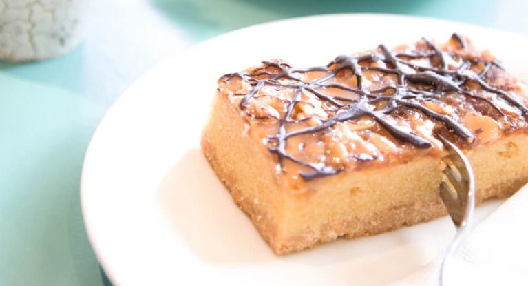 eine Tasse Kaffee neben einem Stück Blechkuchen