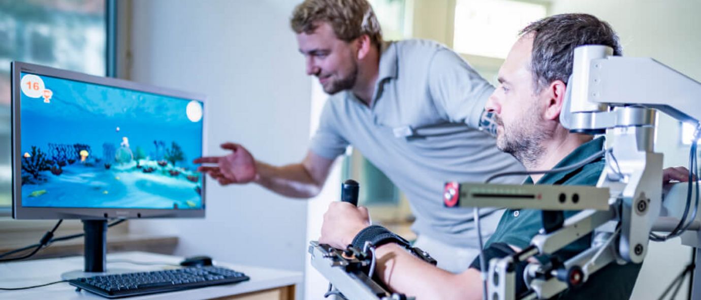 Therapeut unterstützt Patienten beim Armtraining