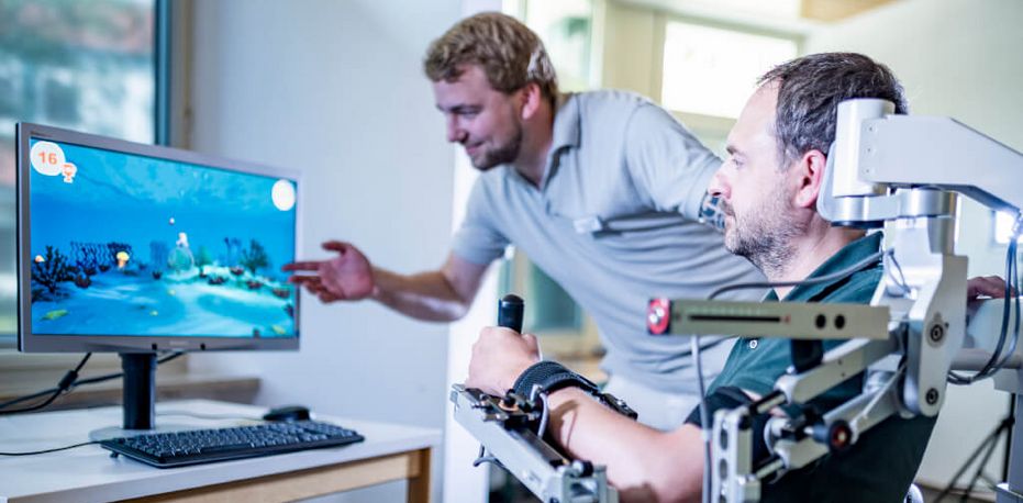 Therapeut unterstützt Patienten beim Armtraining
