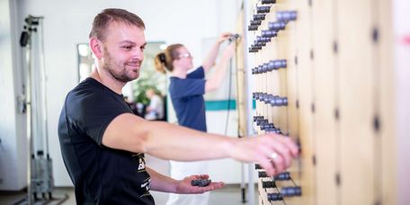 Patient übt in der medizinisch-beruflich orienierten Rehabilitation an einer Griffwand