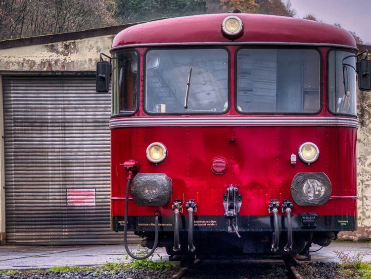Roter Schienenbus steht vor kleinem Lokschuppen