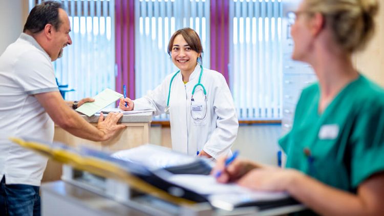 Ärztin und weibliche Pflegekraft sprechen mit einem Patienten