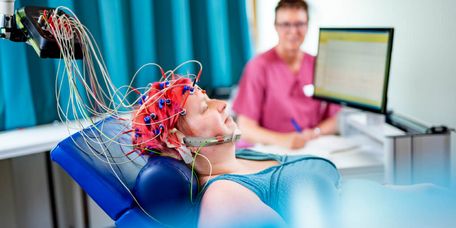 Pflegekraft misst Gehirnströme einer neurlogischen Patientin in der Elektroenzephalografie