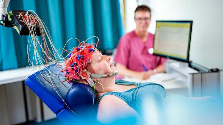 Pflegekraft misst Gehirnströme einer neurlogischen Patientin in der Elektroenzephalografie