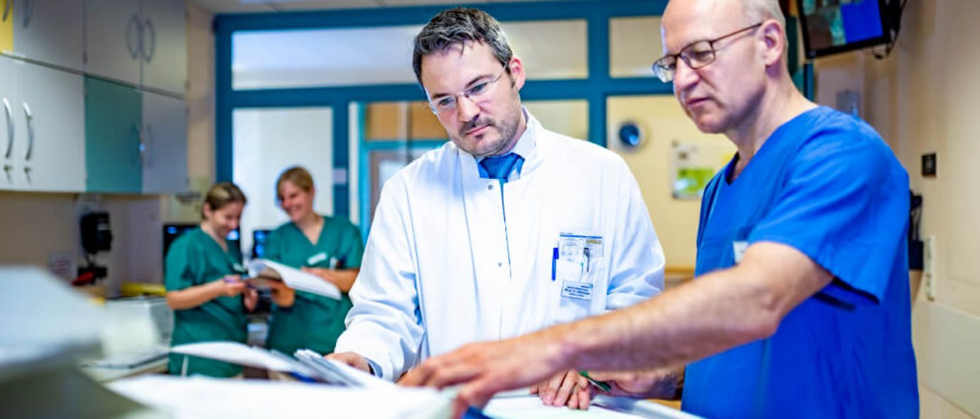 Arzt und Pflegkraft besprechen eine Patientenakte