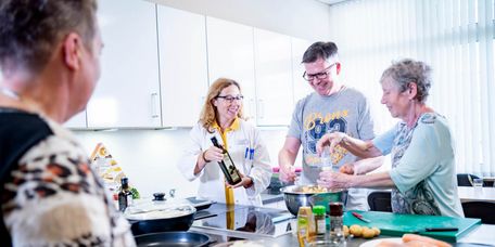 Patienten und Ernährungsberaterin kochen gemeinsamin der Lehrküche