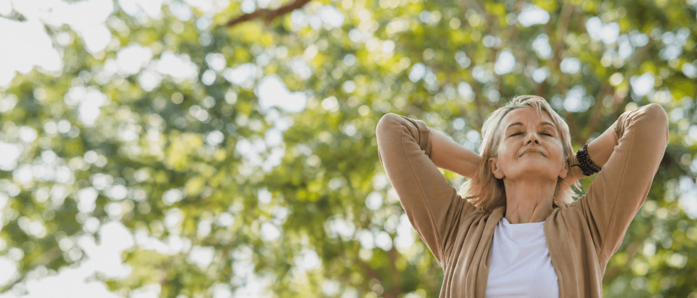 Blonde Frau genießt den Sonnenschein vor einem herbstlichen Baum