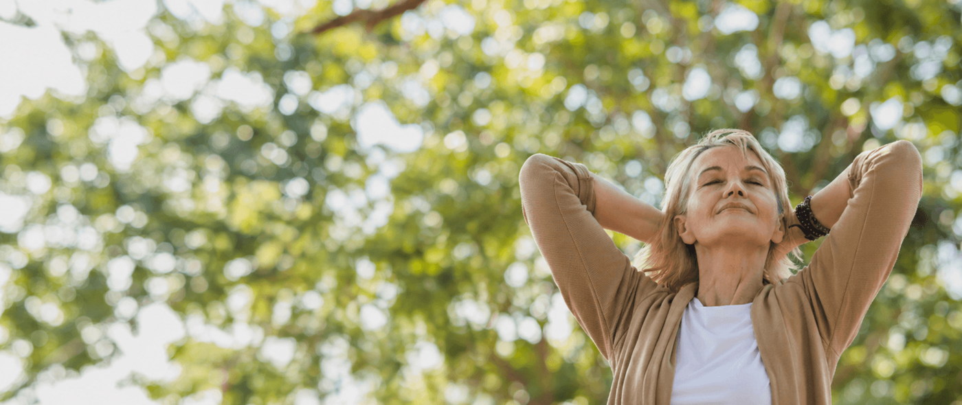 Blonde Frau genießt den Sonnenschein vor einem herbstlichen Baum