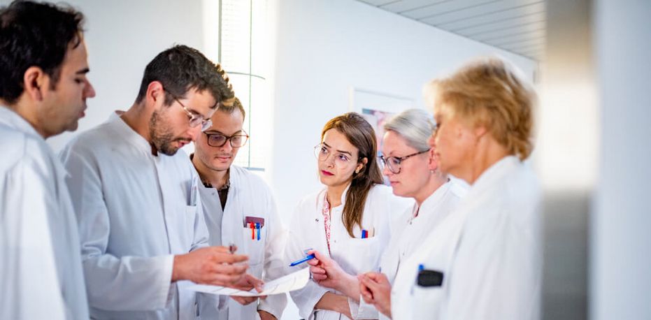 Eine Gruppe männlicher und weiblicher Ärzte diskutiert über eine Patientenakte