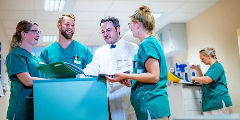 Chefarzt und Pflegekräfte besprechen eine Patientenakte
