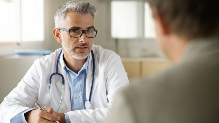 Bärtiger mittelater Arzt spricht mit einem Patienten